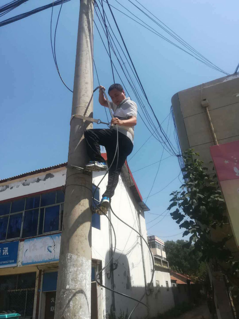 沂山营业部主任巨民德爬上线杆进行抢修工作。